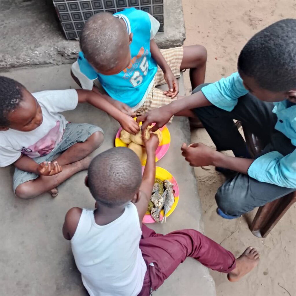 Enfants du centre One Love partageant leur repas assis ensemble